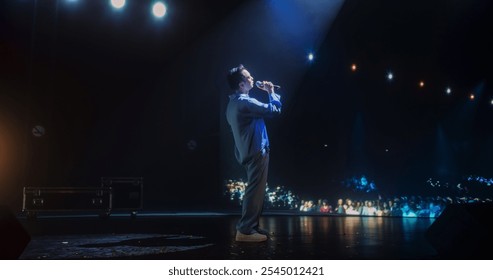 Portrait of a Male Pop Artist Performing Passionately on Stage with Low Key Lighting. Singer with Powerful Vocals and Expressive Gestures Singing a Song in a Dark, Atmospheric Music Hall - Powered by Shutterstock