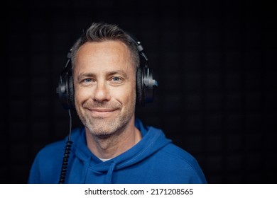 Portrait Of Male Radio Host With Headphones In Studio, Looking At Camera.