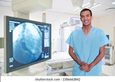 Portrait Of Male Radiologist In Hospital Standing Next To X Ray Displayed On Screen