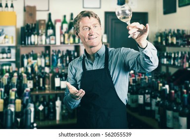 Portrait Of Male Seller In Uniform Promoting To Try Wine Before Purchasing It In Wine Store