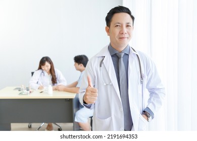 Portrait Of Male Senior Doctor Feeling Good Mood Posing Thumb Up With Doctor And Patient Interaction Together On The Background