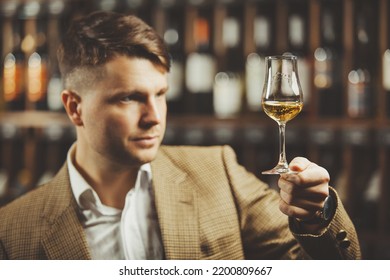 Portrait Of Male Sommelier Tasting Whiskey At Cellar.