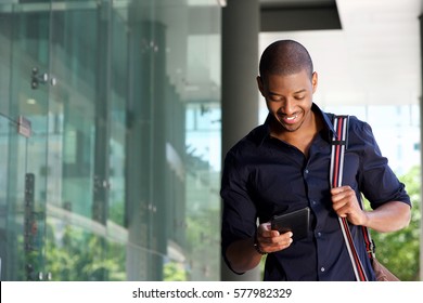 Portrait Of Male Student Walking In City With Tablet And Bag