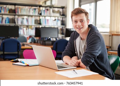 Portrait Of Male Student Working At Laptop In College Library