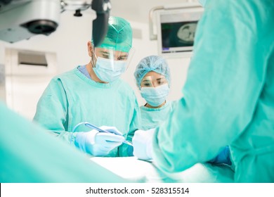 Portrait Of A Male Surgeon Cauterizing Some Wounds On A Patient In The Operating Room