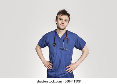 Portrait Of Male Surgeon Standing With Hands On Hips Over Gray Background