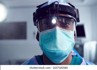 Portrait Of Male Surgeon Wearing Protective Glasses And Head Light In Hospital Operating Theater