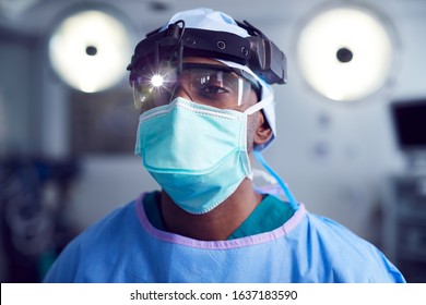 Portrait Of Male Surgeon Wearing Protective Glasses And Head Light In Hospital Operating Theater