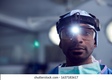 Portrait Of Male Surgeon Wearing Protective Glasses And Head Light In Hospital Operating Theater