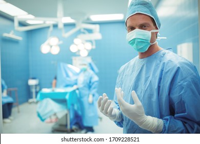 Portrait of male surgeon wearing surgical mask in operation theater at hospital. Healthcare workers in the Coronavirus Covid19 pandemic
