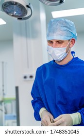 Portrait of male surgeon wearing surgical mask in operation theater at hospital. Modern equipment in operating room. - Shutterstock ID 1748351045
