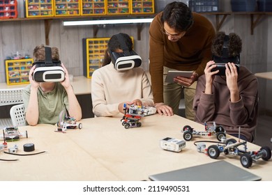 Portrait of male teacher helping group of children wearing VR gear in school and using augmented reality in innovative robotics class - Powered by Shutterstock