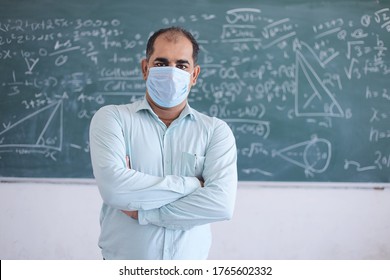 Portrait of male teacher wearing mask standing against blackboard teaching mathematics in classroom, school reopen after lockdown due to covid-19 pandemic. new strain of coronavirus, omicron cases  - Powered by Shutterstock