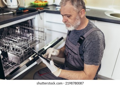 Portrait Of Male Technician Repairing Dishwasher In Kitchen using digital tablet. - Powered by Shutterstock