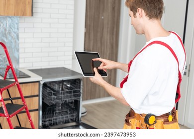 Portrait Of Male Technician Repairing Dishwasher In Kitchen using digital tablet. - Powered by Shutterstock