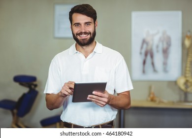 Portrait of male therapist holding digital tablet in clinic