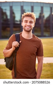 Portrait Of Male University Or College Student Standing Outdoors By Modern Campus Building