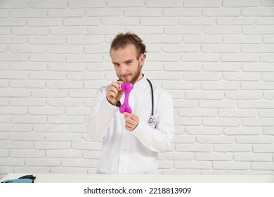 Portrait Of Male Veterinarian In White Robe With Curly Hair In Headband Showing Rubber Rose Dog Toy For Chewing While Teething. True Specialist Always Ready Help Our Little Brothers - Animals.