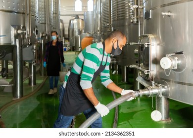 Portrait Of Male Winery Worker In Mask Working With Metal Tanks For Wine Fermentation