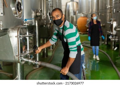 Portrait Of Male Winery Worker In Mask Working With Metal Tanks For Wine Fermentation