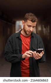 Portrait Of A Man 20-30 Years Old Looking At The Phone On The Street, Using The Phone