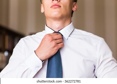 Portrait of a man adjusting his shirt and tie
