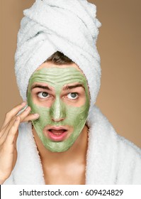 Portrait of man applying avocado facial mask to face. Photo of well groomed man receiving spa treatments. Beauty & Skin care concept