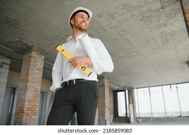 Portrait Of Man Architect At Building Site. Confident Construction Manager Wearing Hardhat. Successful Mature Civil Engineer At Construction Site With Copy Space