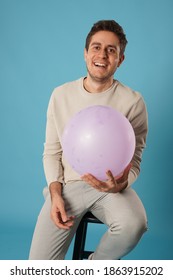Portrait of man with balloon in front of blue background in the studio