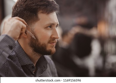 Portrait of man with beard and pipette oil for hair care. Concept Barbershop