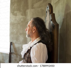 Portrait of a man with a beard in profile in vintage clothing, looking out the window on a gray background. Cosplay. - Shutterstock ID 1788992450