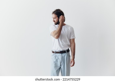 Portrait Of A Man With A Black Thick Beard And Long Hair In A White T-shirt On A White Isolated Background Emotion Of Sadness And Longing