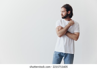 Portrait Of A Man With A Black Thick Beard And Long Hair In A White T-shirt On A White Isolated Background Emotion Of Sadness And Longing