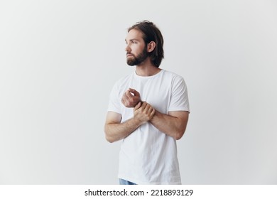 Portrait Of A Man With A Black Thick Beard And Long Hair In A White T-shirt On A White Isolated Background Emotion Of Sadness And Longing