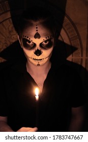 Portrait of a man in a black T-shirt on a light background, with a Halloween skull make up to show his emotions. Halloween party or horror theme. Mexican culture.