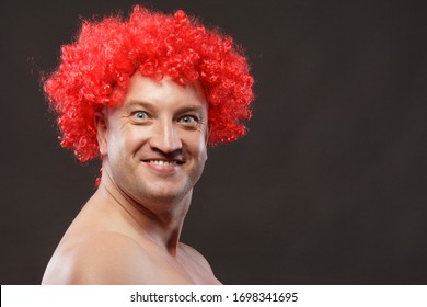 Portrait of a man in a bright red curly wig, funny facial expressions, on the background.