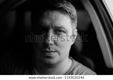 Portrait of a man in a car close-up in black and white tones. Monochrome photo. Low key.