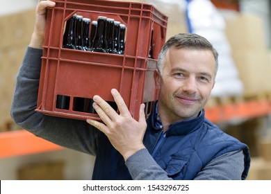 portrait of man carrying crate of beer