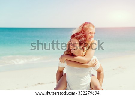Portrait of man carrying girlfriend on his back on the beach