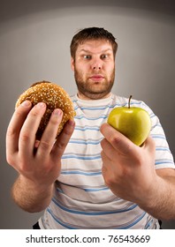 Portrait of man choosing between hamburger and green apple