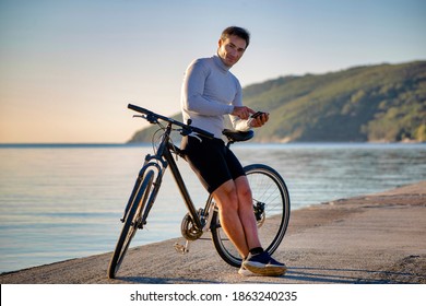 Portrait of a man cyclist with phone on bicycle outdoors near the sea