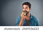 Portrait, man and eating apple for nutrition, healthy diet or wellness isolated on gray studio background space. Happy, face or hungry person with fruit for natural organic food or vitamin c benefits