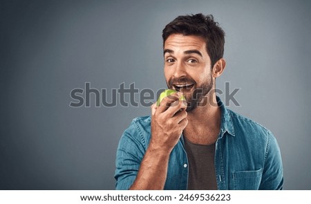 Portrait, man and eating apple for nutrition, healthy diet or wellness isolated on gray studio background space. Happy, face or hungry person with fruit for natural organic food or vitamin c benefits