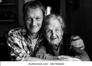 Portrait Of Man Embracing His Grandmother. Black And White Photography.