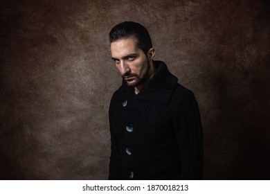 Portrait Of A Man. Evil Look. Guy In A Black Sweater. Portrait On A Brown Background.