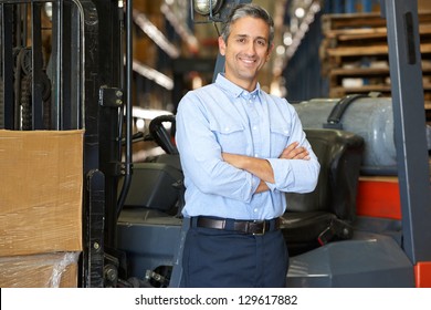 Portrait Of Man With Fork Lift Truck In Warehouse