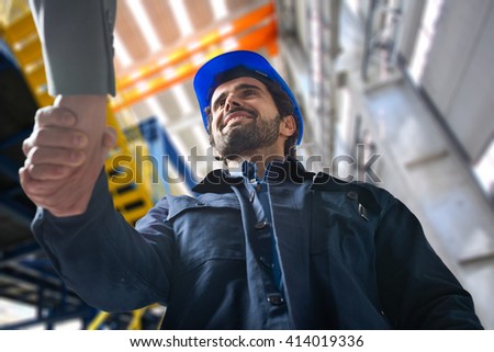 Portrait of a man giving an handshake in an industrial facility