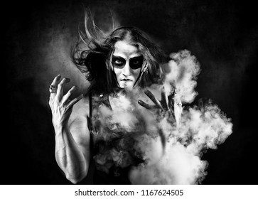 Portrait Of Man In Goth Style Clothes With Scull Makeup. Blowing The Smoke.