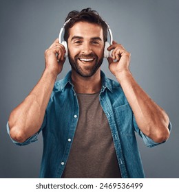 Portrait, man and headphone for hands in studio, audio media and podcast or ebook on gray background. Technology, streaming and music subscription for song, male person and smile for listening - Powered by Shutterstock