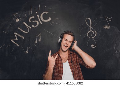 Portrait of man in headphones listening music and showing rock gesture